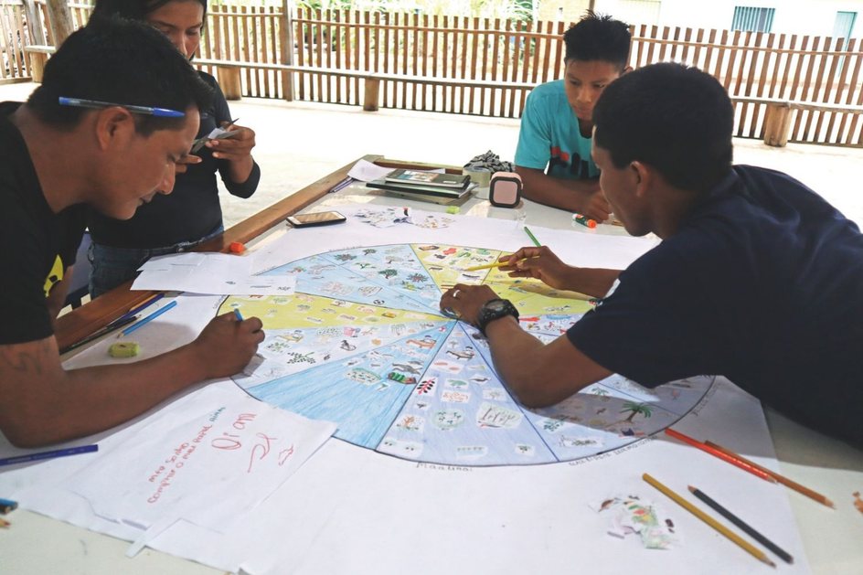 Legenda: Na comunidade Santana, Rio Quiari, região do Médio Içana, agentes fazem o desenho do ciclo anual em 2024. CRÉDITO: GISELLE SOUSA_INSTITUTO SOCIOAMBIENTAL