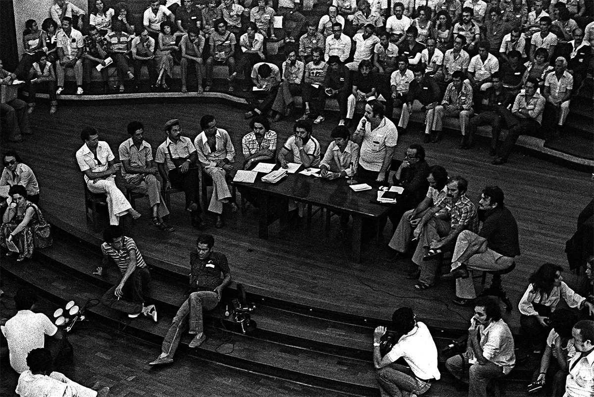 Plenária de fundação do PT no Colégio Sion. Olívio Dutra (primeiro à esquerda, sentado na mesa), sobre o futuro do partido: “Nem mesmo o Lula pode ser a saída. Não é apenas uma pessoa que tem que retomar e requalificar a relação com os movimentos sociais.”
